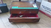 Closed wooden box with metal latch showing lot sticker and condition label.