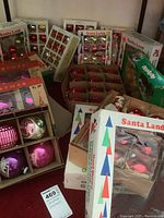 Overall view of six cardboard boxes containing glass Christmas ball ornaments in various sizes and colors.