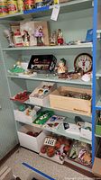 Shelf with various Christmas ornaments and figurines including boxed items and a decorative clock