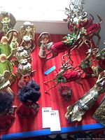 Ceramic angels, painted plastic deer, and a handcrafted nativity arranged on red cloth.