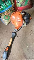 Complete view of the orange Echo SRM-225 gas weed eater laid on the ground showing handle, engine housing, and fuel tank.