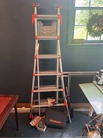 Overview of ladder system assembled in A-frame configuration with accessories laid out in front