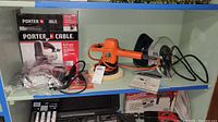 Shelf view showing Porter Cable orbital jigsaw in box, Black & Decker orange orbital polisher, and Powr-Kraft circular saw with plastic damage and attached power cords.
