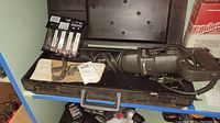 Reciprocating saw in case with blades and accessory tools on table