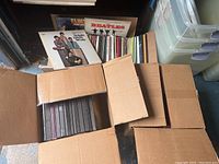 Wide shot of three boxes filled with 33RPM vinyl records, view of album covers including The Beatles and Elvis Presley.