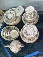 Photo showing the full set of Royal Worcester Lavinia china including plates, cups, saucers, berry bowls, soup bowls, and teapot with lid arranged on carpet.