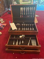 Open wooden box showing flatware organized in lid and drawers