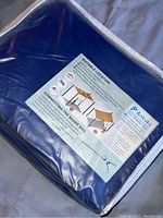 View of the blue sun shade sail in original packaging with label showing product information and installation instructions.