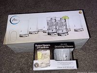 Photo showing box of Chrisholm brand tall drinking glasses, set of 10, and box of Better Homes & Gardens branded drinking glasses, set of 4, all brand new and boxed.
