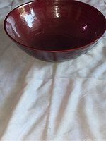 Side view of the red designer bowl showing its wide opening and curved shape.
