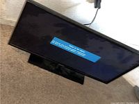 Samsung TV powered on showing initial startup message, plugged in and functioning.