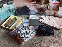 Overall view of sewing lot with storage container, books, patterns, and fabric bags spread out on carpet