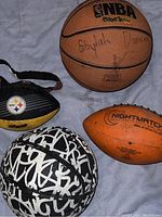 Four sports balls including basketballs, football, and headband arranged on cloth surface