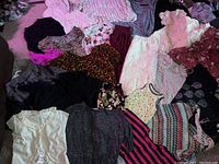 Photo of various women's clothing items including tops, blouses, skirts, and dresses in assorted patterns and colors.