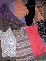 Overview photo of eight women's dresses arranged on floor showing variety in colors and patterns including polka dots, coral, black, multicolor, leopard print, peach, beige lace, and purple with ruffles.