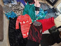 Photo of a variety of women's dresses and tops spread on the floor with different colors and patterns including Christmas dress, floral, animal print, and solid colors.