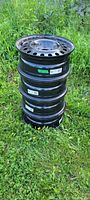 Stack of four black steel rims placed on grass, showing overall condition and design