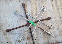 Four cross-shaped four-way wrenches arranged with visible rust and dust throughout.