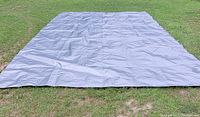 Full view of grey tarp spread on grass showing overall size and condition.