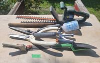 Full lot displayed showing the hedge trimmer, clipper, shears, sprayer, and other tools on a table.