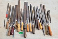Full view of assorted metal files with wooden and metal handles, laid out on a white surface. Files vary in shape and size.