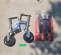 Photo of two metal gate tracking wheels with springs and mounting brackets next to a new gate latch hardware kit in original sealed packaging labeled Builder's Choice.