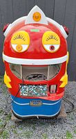 Full front view of the red and blue robot head themed vending machine with yellow eyes, coin slot, gumball window, and 'Thank You' plate.