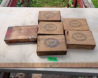Photo showing 6 vintage wooden cigar boxes arranged on a white surface with a ruler for scale. Five boxes have similar stamping from C. De Graaff, and one box is marked Chicago II. Boxes show vintage wear and need cleaning.