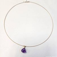 Thin yellow gold wire choker laid flat showing overall style with central amethyst pendant