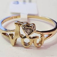 Close-up photo of 10K yellow gold ring showing the front design with the words 'I love you' and a small diamond in a heart shape.