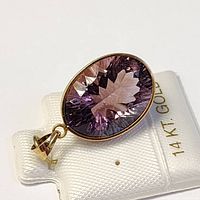 Photo of the oval faceted deep purple amethyst pendant set in 14K yellow gold bezel with integrated bail, displayed on a 14K gold jewelry card.