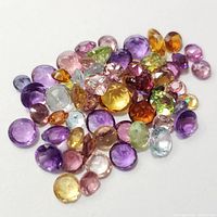 Top view of assorted loose faceted gemstones showing variety of colors and cuts on a white background.