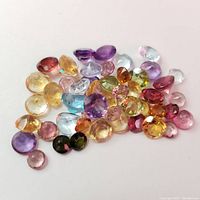 Loose assorted faceted gemstones in multiple colors and shapes on a white background.