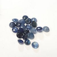 Loose blue sapphire gemstones showing various cuts and shades of blue on white background.