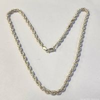 Full view of silver rope chain necklace laid flat showing entire length and clasp.
