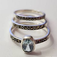 Close-up front view of the silver ring set showing the oval blue topaz stone and marcasite decorated bands