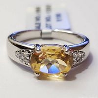 Close-up front view of sterling silver ring with oval citrine stone and CZ accents.