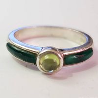 Front view of silver ring showing round light green peridot cabochon center stone with green onyx inlays on band.