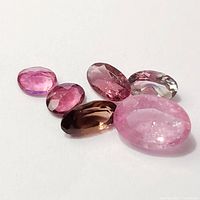 Close-up of six loose tourmaline gemstones in various pink and brown shades showing colors and cuts