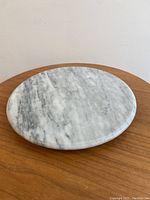 Top view of round Carrara marble lazy Susan showing natural veining and polished surface.