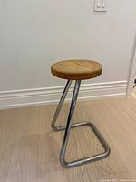 Side angle view of the tubular chrome frame and wooden seat showing vintage wear.