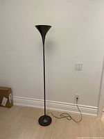 Full view of the vintage torchiere floor lamp standing upright against a wall on a light wood floor.