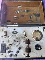 Top view of Aloe Co. electrotherapy device inside brown travel case, showing metal clips and control switches