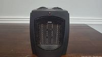 Front view of black ceramic heater showing protective mesh and heating elements inside.