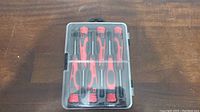 Front view of the plastic case containing five mini screwdrivers with visible red and black handles.