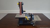 Stationary sander with vertical belt and horizontal disc viewed frontally on table