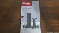 Photo of the electric wine set box showing all included items: electric opener, aerator, vacuum pump, stoppers, foil cutter.