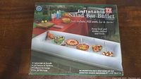 Photo of box showing Inflatable Salad Bar Buffet brand and product use outdoor on table with multiple dishes in it.