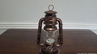 Front view of copper-tone battery lantern with glass globe and metal handle
