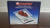 Front of the box showing Starfrit branding and an image of the scale with strawberries on the glass platform.